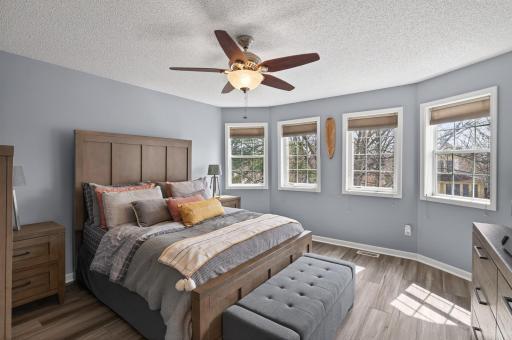 Spacious primary bedroom with multiple windows, fresh paint, brand new luxury vinyl plank (LVP) flooring, and abundant natural light.