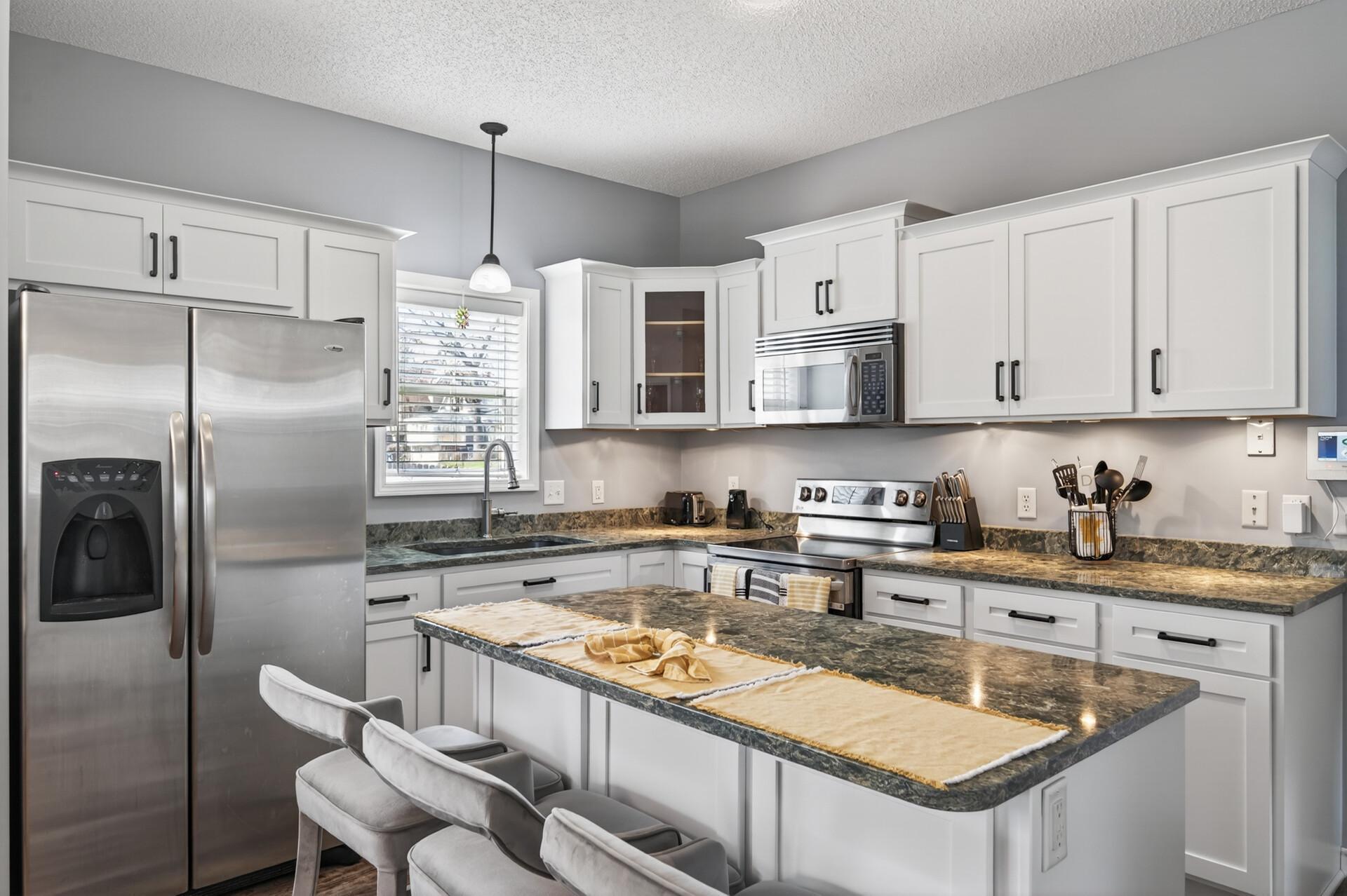 Updated kitchen featuring refaced cabinetry with modern hardware, stainless steel appliances, and a clean, refreshed look. The center island offers additional prep space and casual seating.