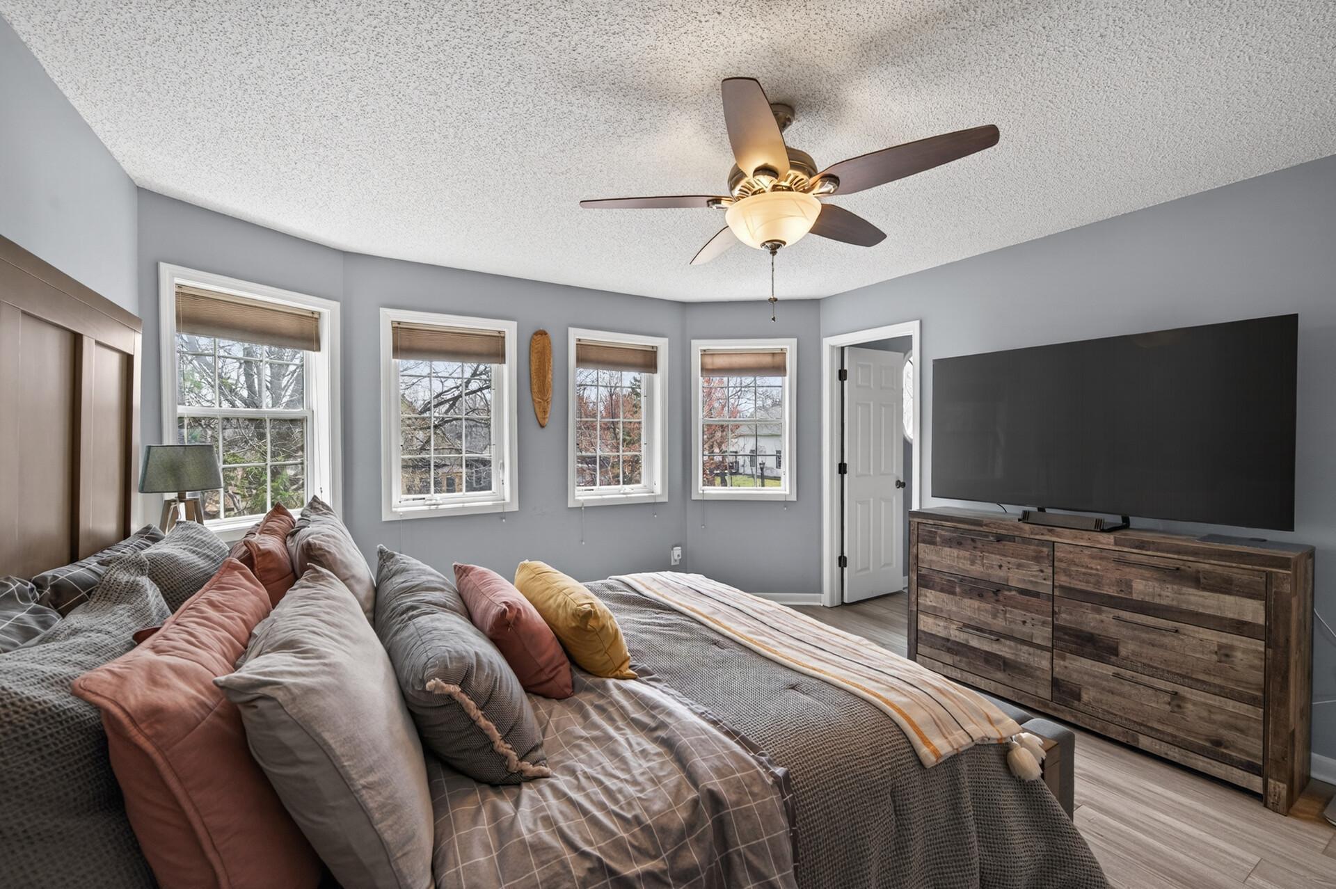Additional view of the primary bedroom featuring large windows, a walk-in closet, and brand new luxury vinyl plank (LVP) flooring that fills the space with abundant natural light.