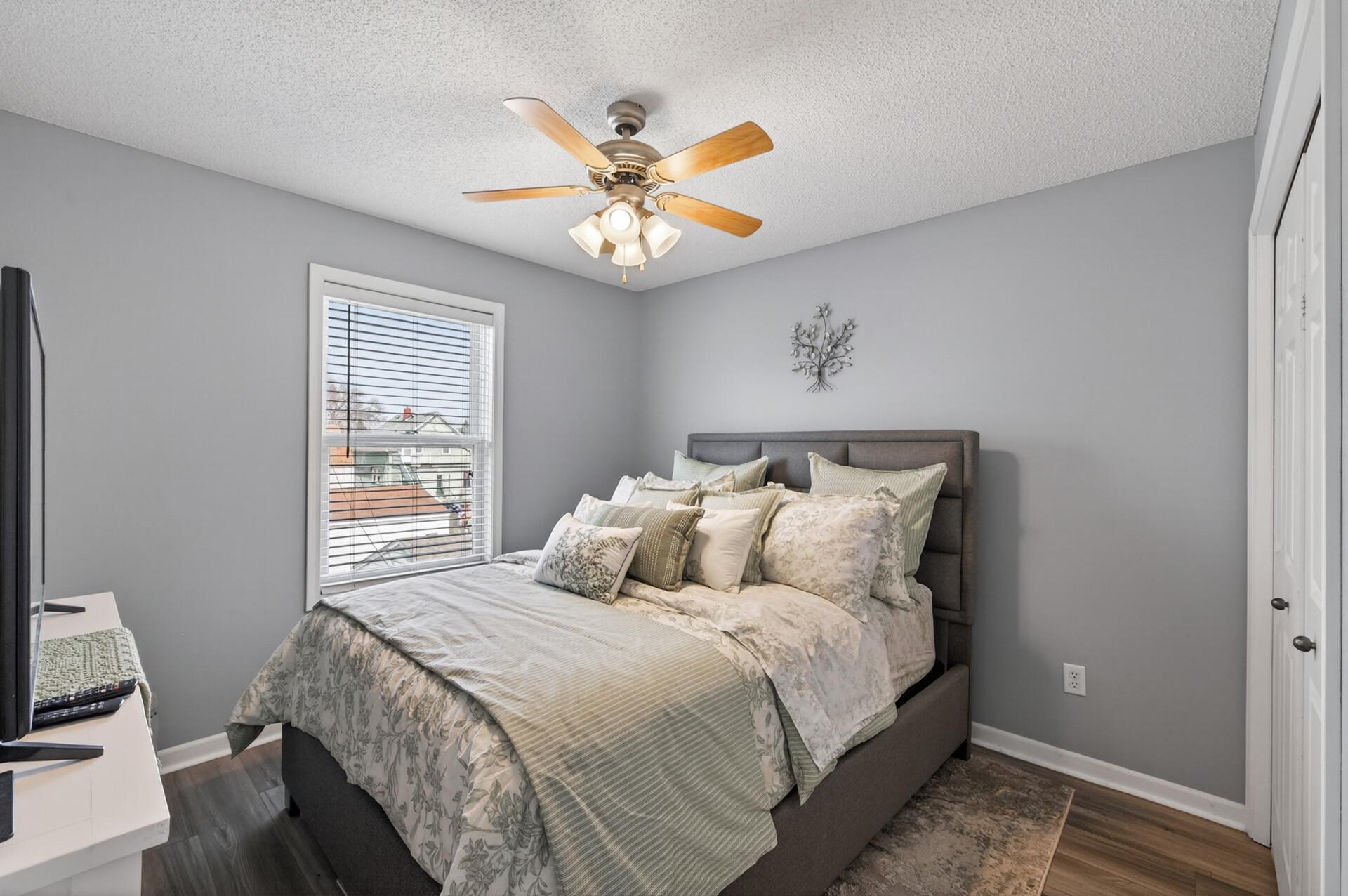 Cozy second bedroom featuring brand new luxury vinyl plank (LVP) flooring, fresh paint, neutral tones, a ceiling fan, and abundant natural light.