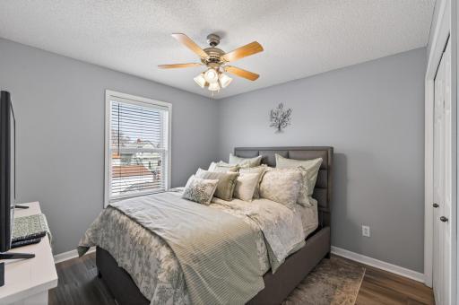 Cozy second bedroom featuring brand new luxury vinyl plank (LVP) flooring, fresh paint, neutral tones, a ceiling fan, and abundant natural light.