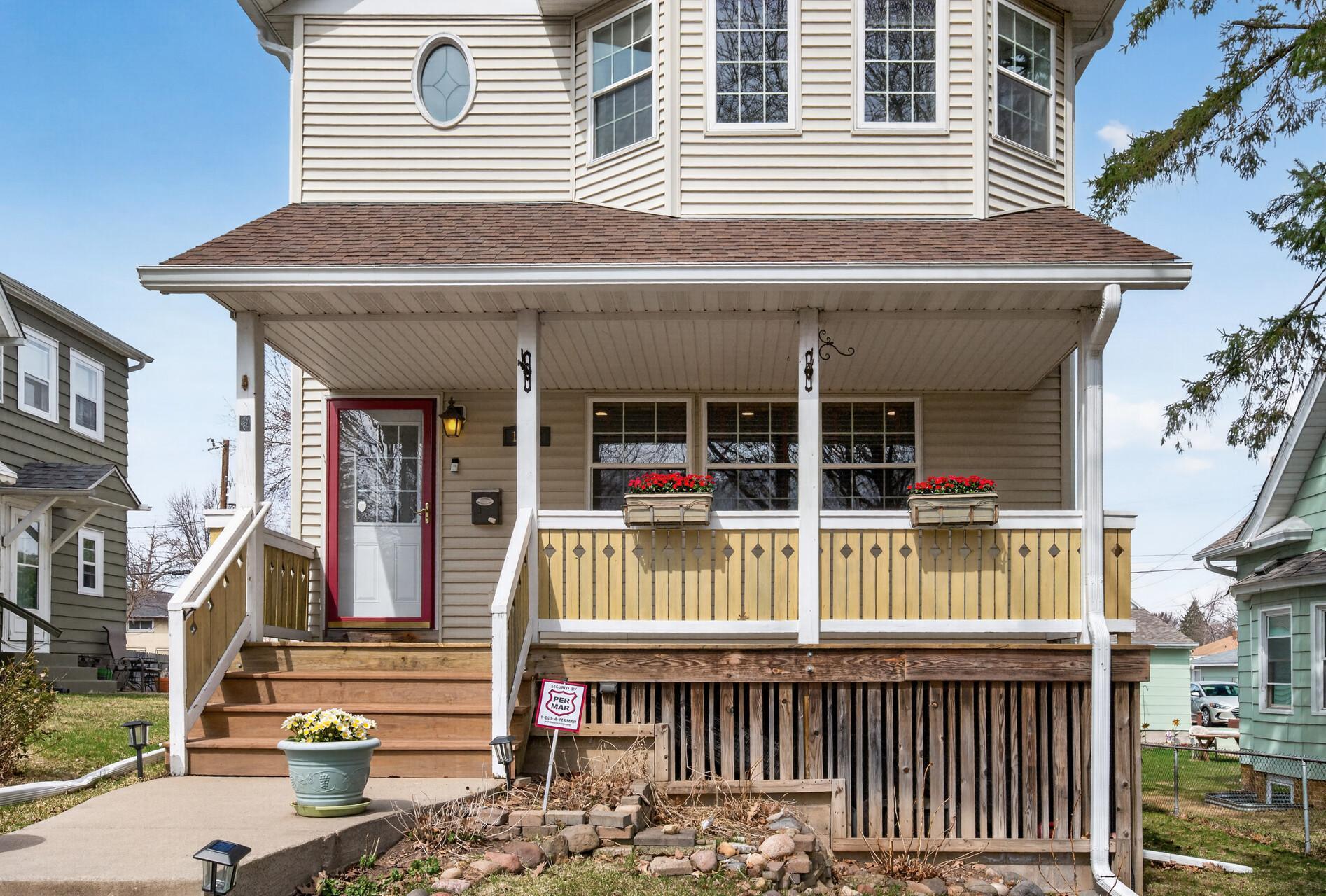 Charming two-story home with inviting curb appeal, featuring a welcoming front porch and mature trees. The elevated lot offers added privacy, complemented by a well-maintained walkway leading to the entrance.