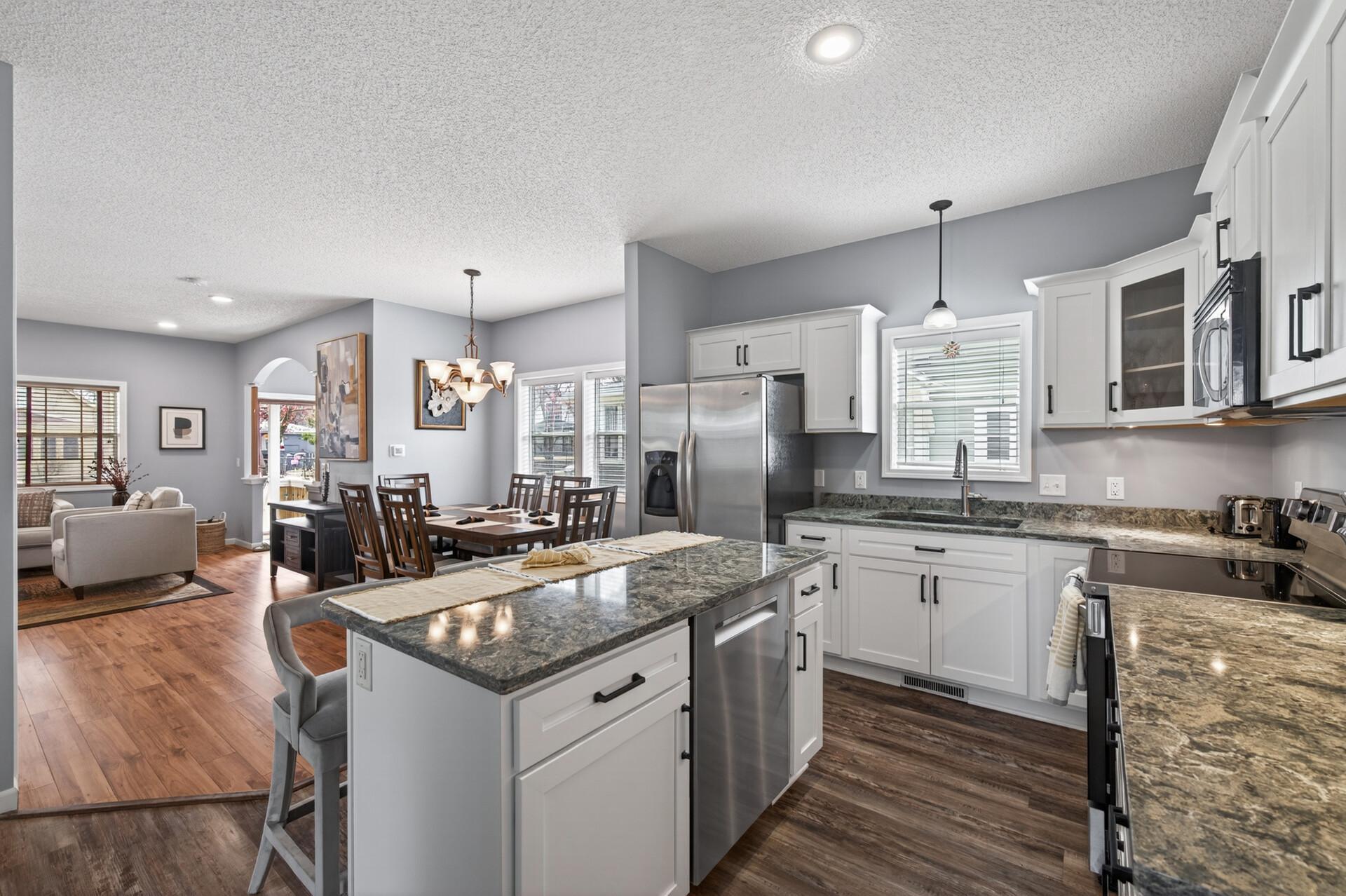 Bright, modern kitchen with white cabinetry, granite countertops, and seamless connection to the dining space.