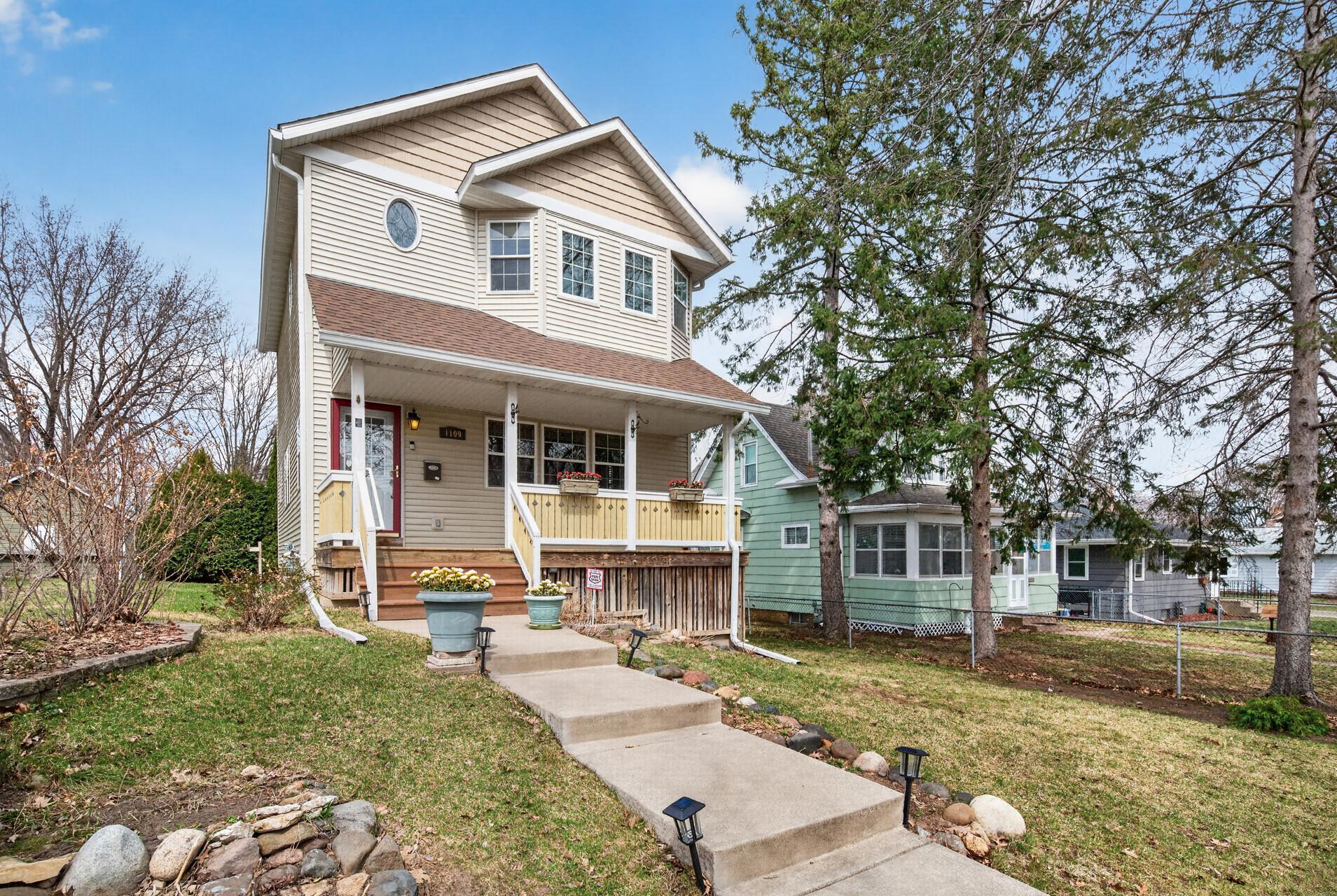 Beautiful front elevation showcasing classic architectural details and a spacious covered porch, perfect for relaxing. The landscaped yard and surrounding homes enhance the overall charm of the block.