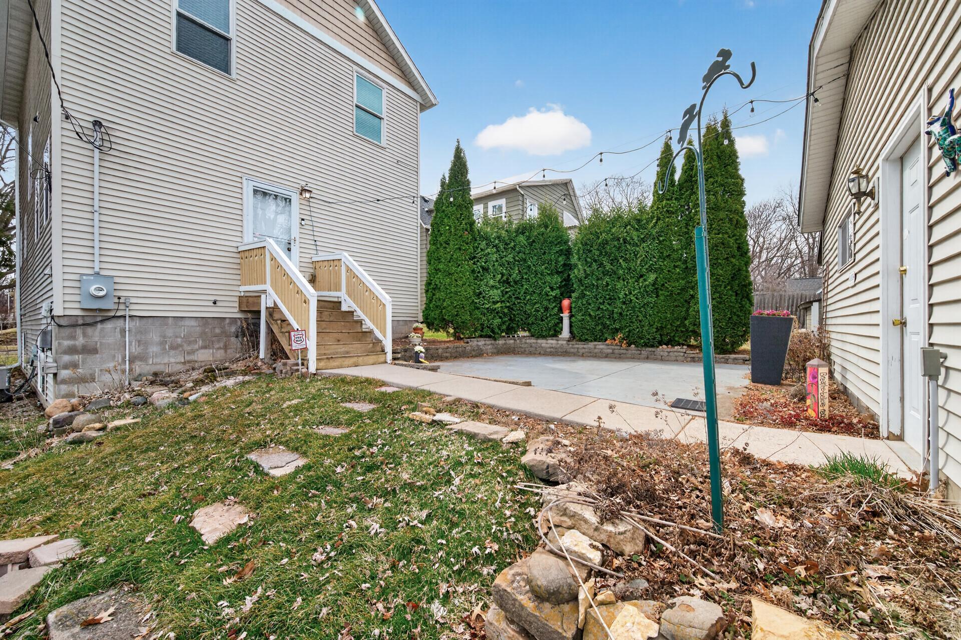 Concrete patio space ideal for outdoor seating or entertaining, with surrounding greenery providing privacy and charm.