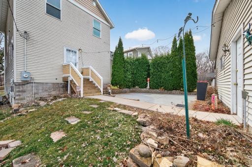 Concrete patio space ideal for outdoor seating or entertaining, with surrounding greenery providing privacy and charm.