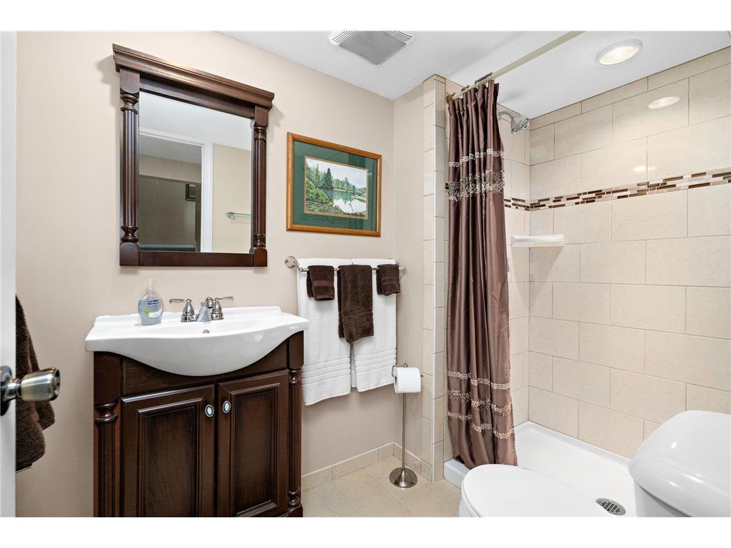 Lower level modern 3/4 bathroom featuring a tiled walk-in shower with updated fixtures, and a stylish vanity, offering a clean and contemporary feel.