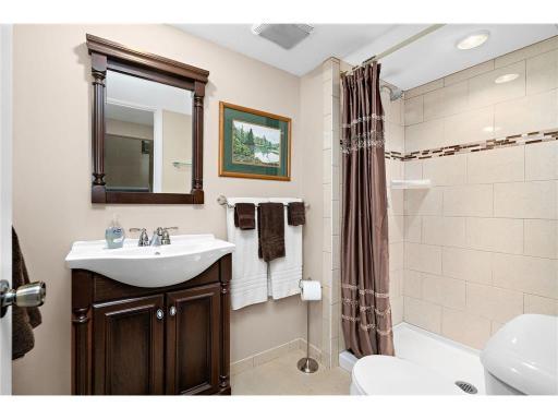 Lower level modern 3/4 bathroom featuring a tiled walk-in shower with updated fixtures, and a stylish vanity, offering a clean and contemporary feel.