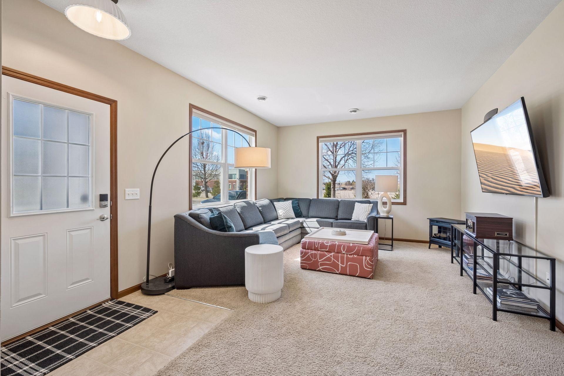Spacious living room with large windows. Windows face south and west, providing wonderful sunlight. Great in the winter! There are blinds on all the windows. Please exclude electric fireplace.