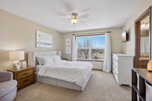 Roomy primary bedroom with large windows, space for dressers and reading chair.