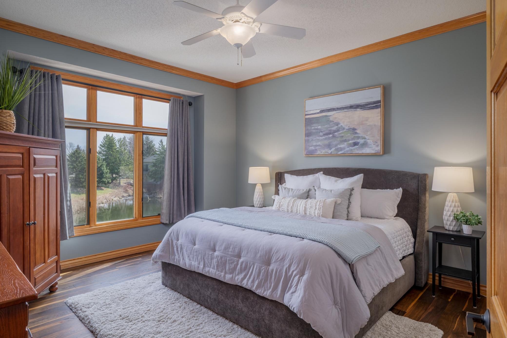 This luxurious primary suite is on the main floor and overlooks serene pond views.