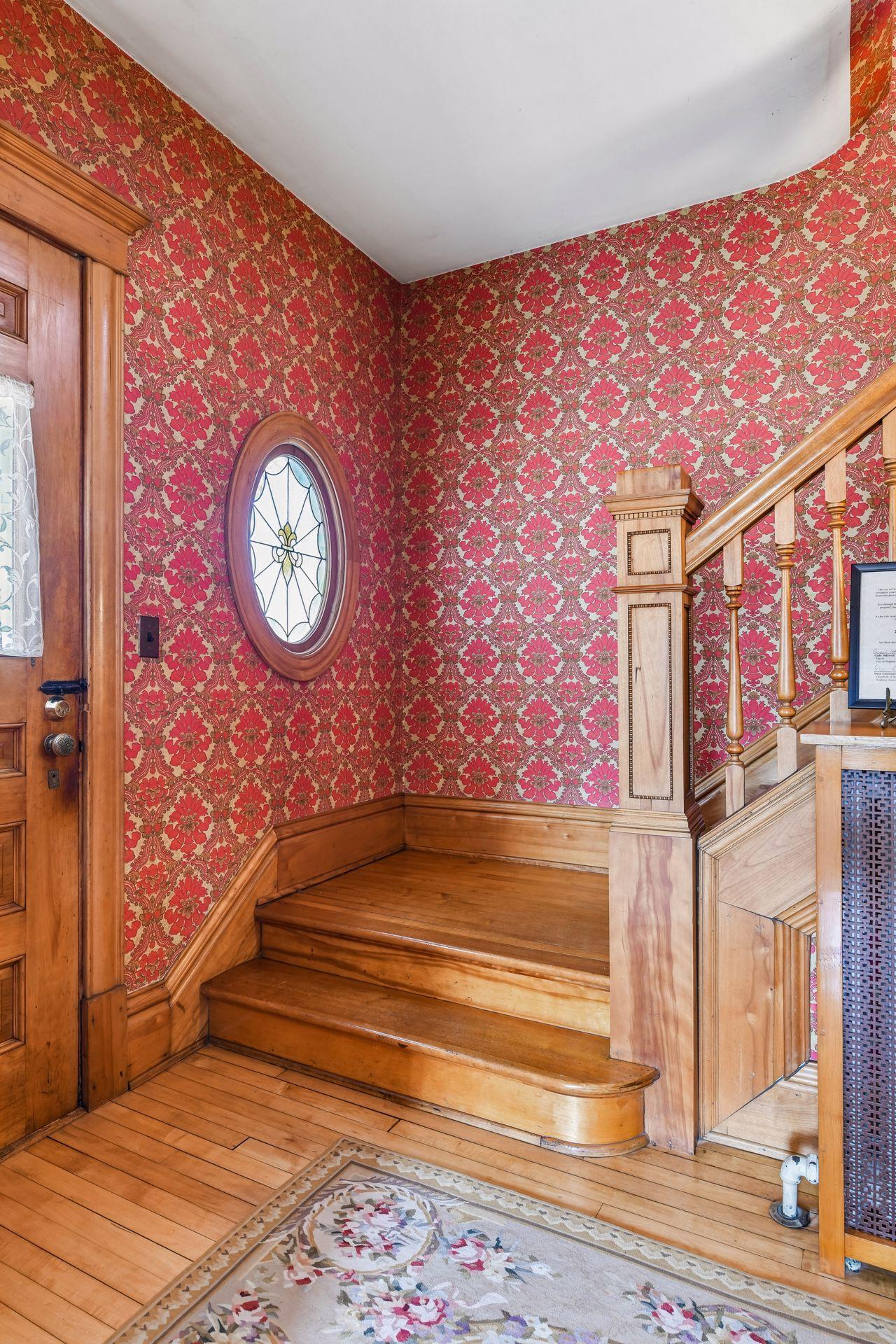 Step into a spacious foyer where maple floors, a gorgeous banister, and a stained-glass window make a memorable first impression.