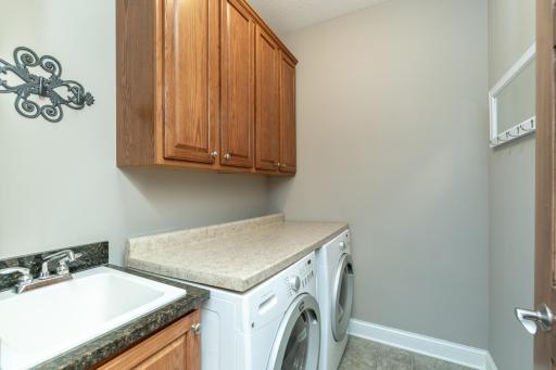 Main floor laundry with tub and storage cabinets