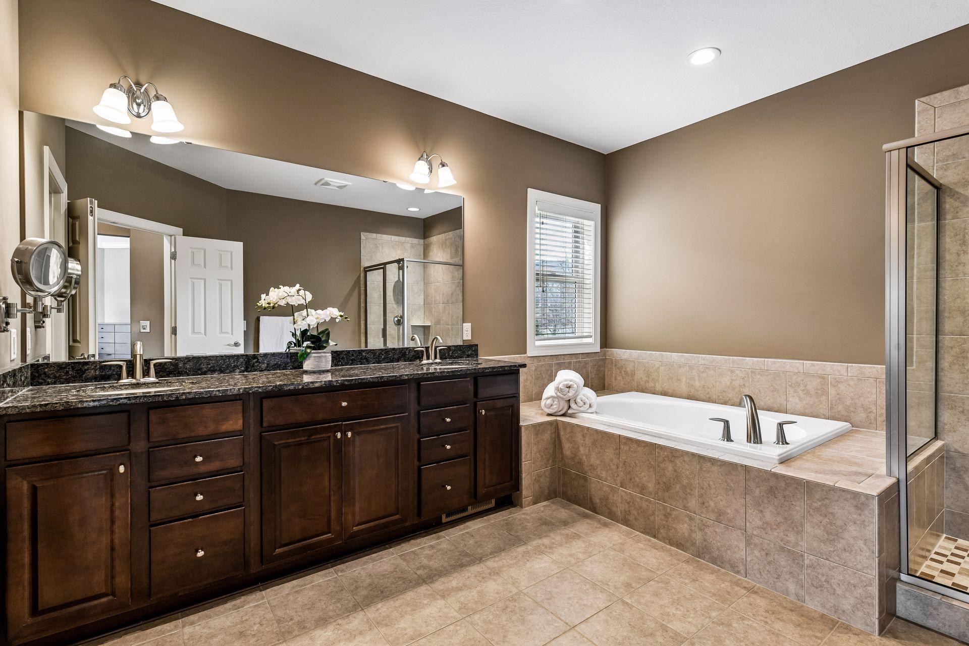 Spacious primary bath featuring dual sinks, soaking tub, separate shower, and timeless finishes.