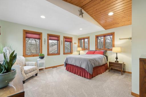 View of the spacious main floor bedroom overlooking the shores of Pickeral Lake. The tongue and groove ceiling gives this space an "up north" feel while being about an hour from the Twin Cities metro.