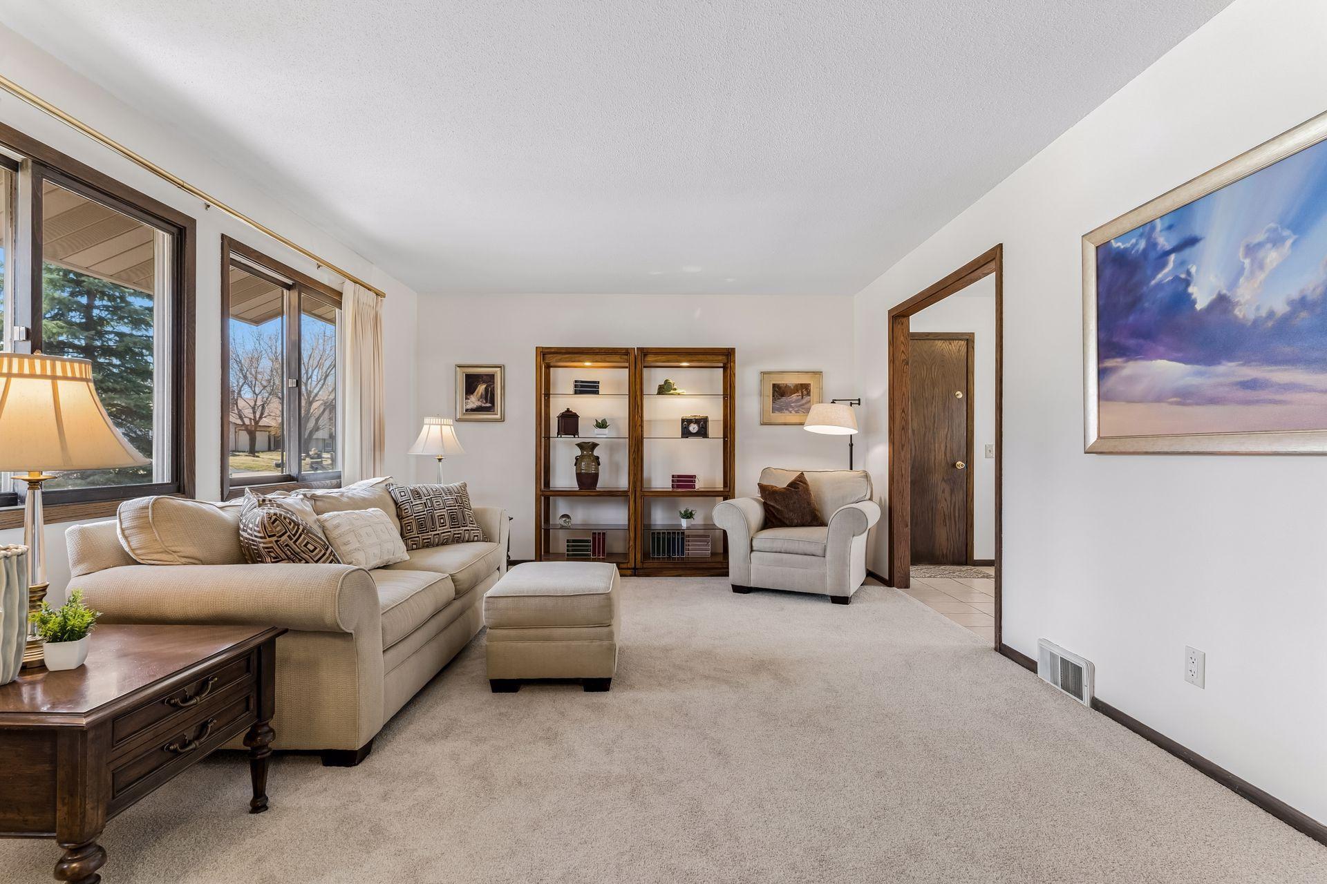 Bright and spacious living room with large windows, abundant natural light, neutral finishes, and new carpeting, ideal for everyday living and entertaining.