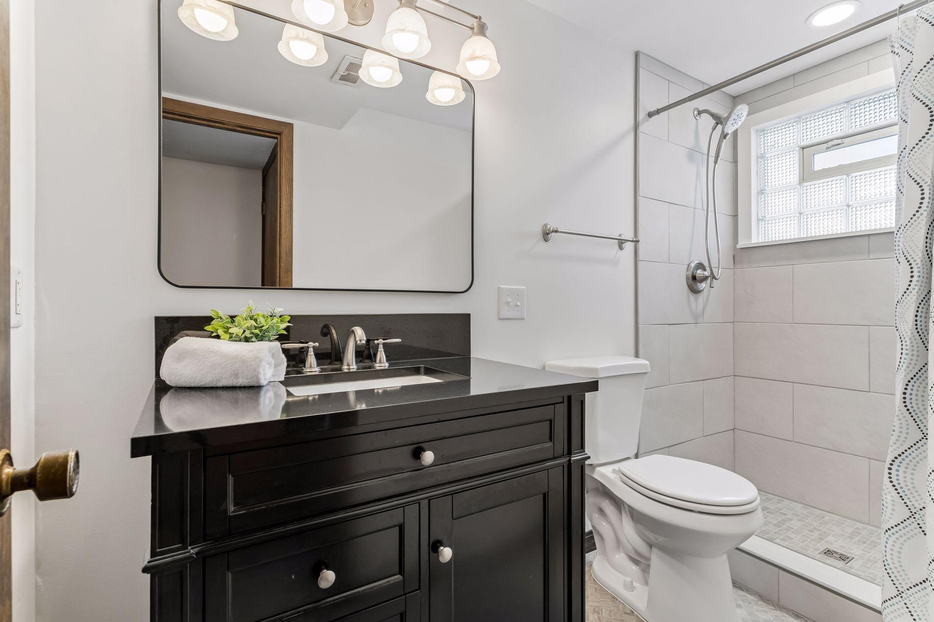 Updated lower-level bathroom (2026) featuring modern vanity, solid surface countertop and tiled walk-in shower.