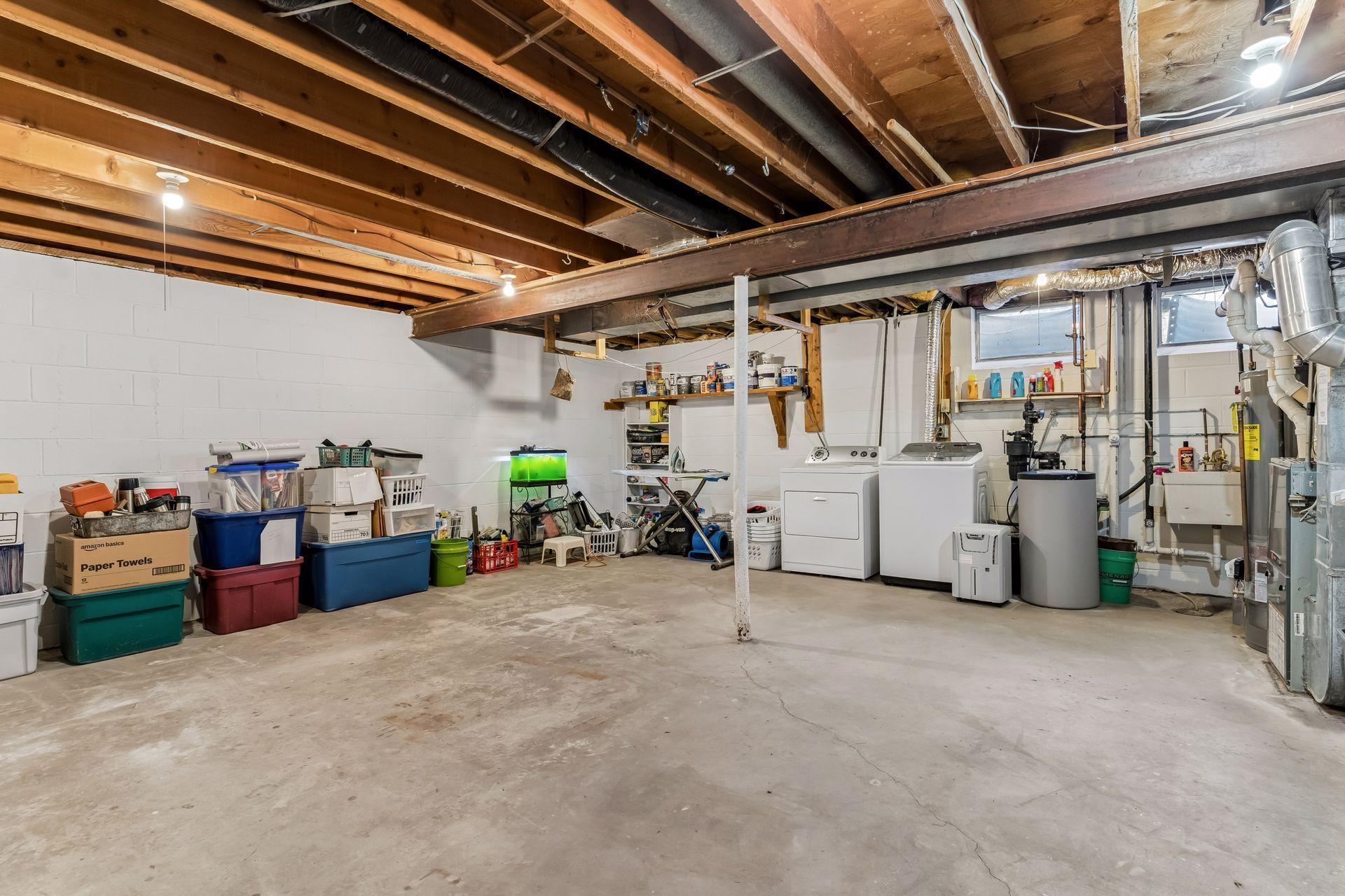 Unfinished basement area offering ample storage space, laundry area, and potential for future finishing. Utility and storage space with washer, dryer, HVAC system, and room for organization or hobby use.