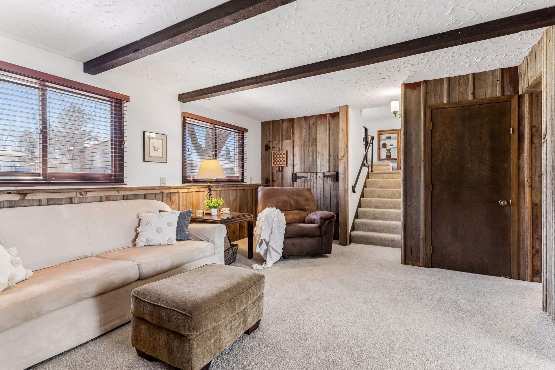 Lower-level living area with wood accent walls, beam ceilings and open layout, offering flexible space for recreation or relaxation.
