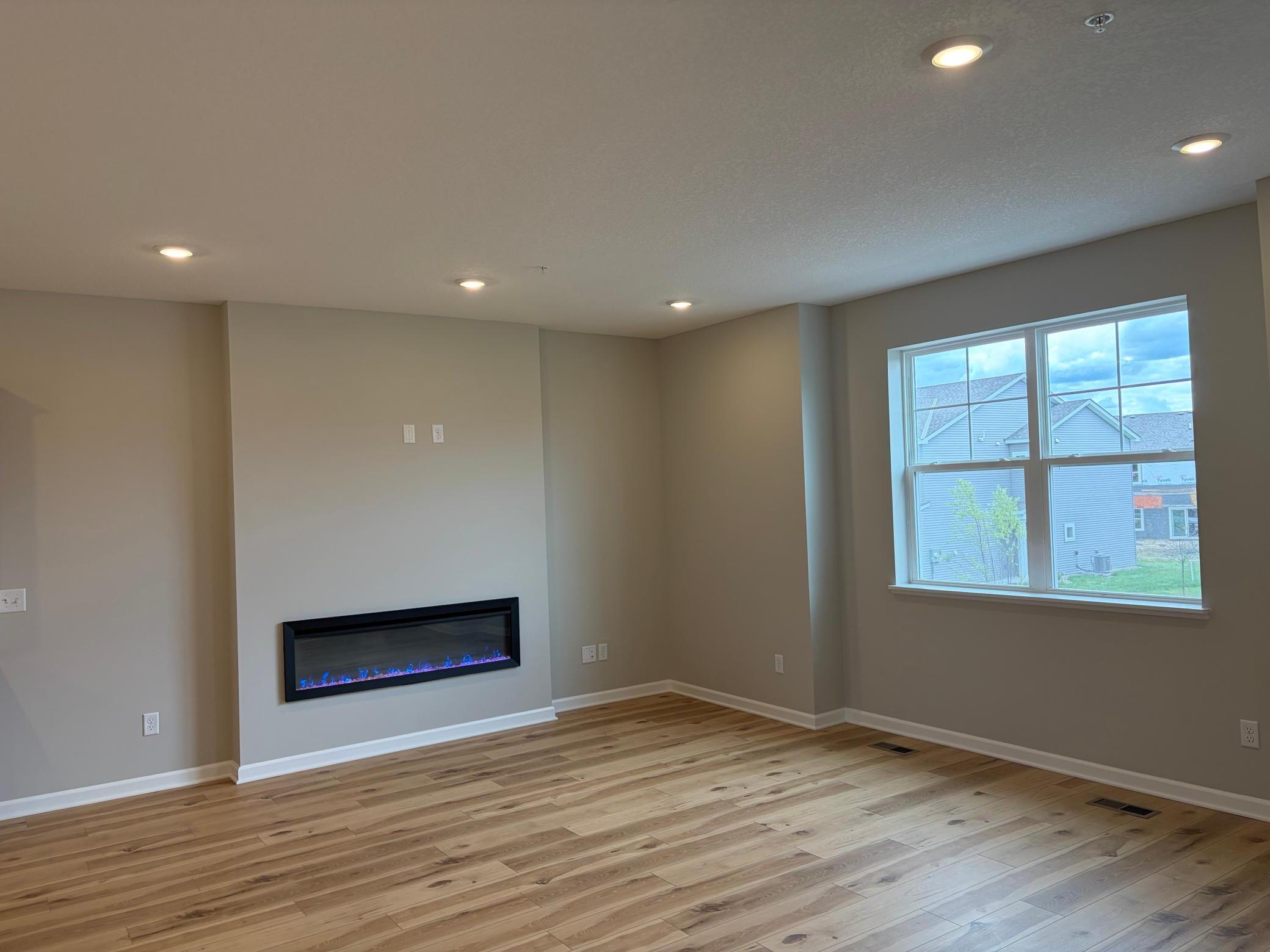 This spacious living room has excellent scenery featuring large windows, a fireplace, and enough space for even the biggest couches.