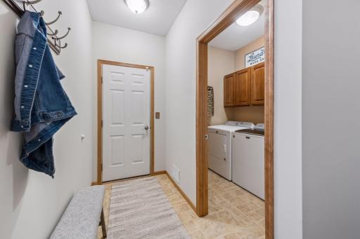 Back foyer from garage offers space to hang your coat and features adjacent laundry room with built-ins and handy sink.