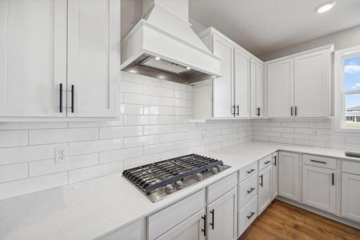Quartz countertops and a crisp white tile backsplash tie the kitchen together. Photo of model home, color & options will vary.