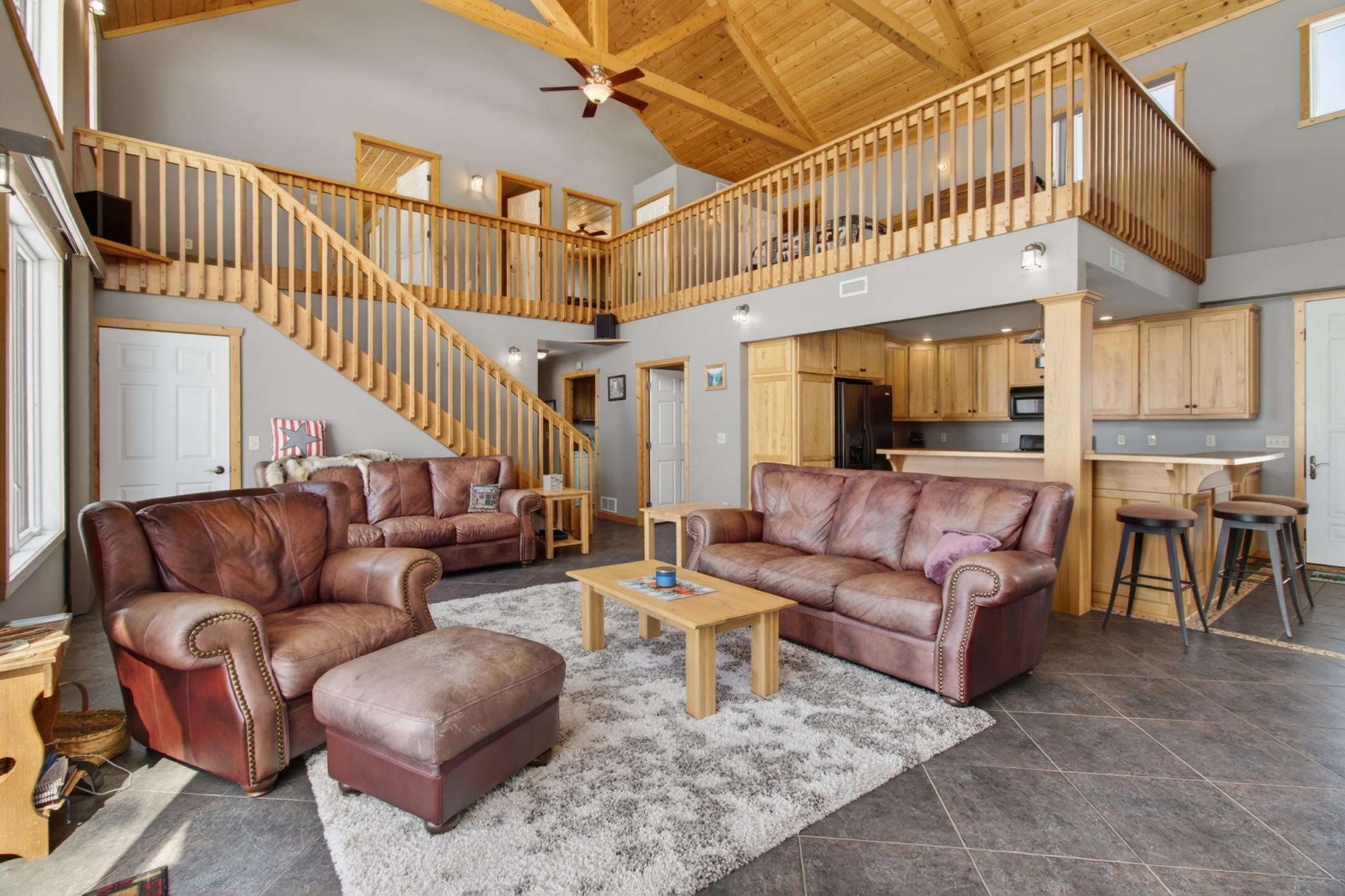 Two Story Living Room w/Vaulted Ceilings and Decorative Wood Rafters