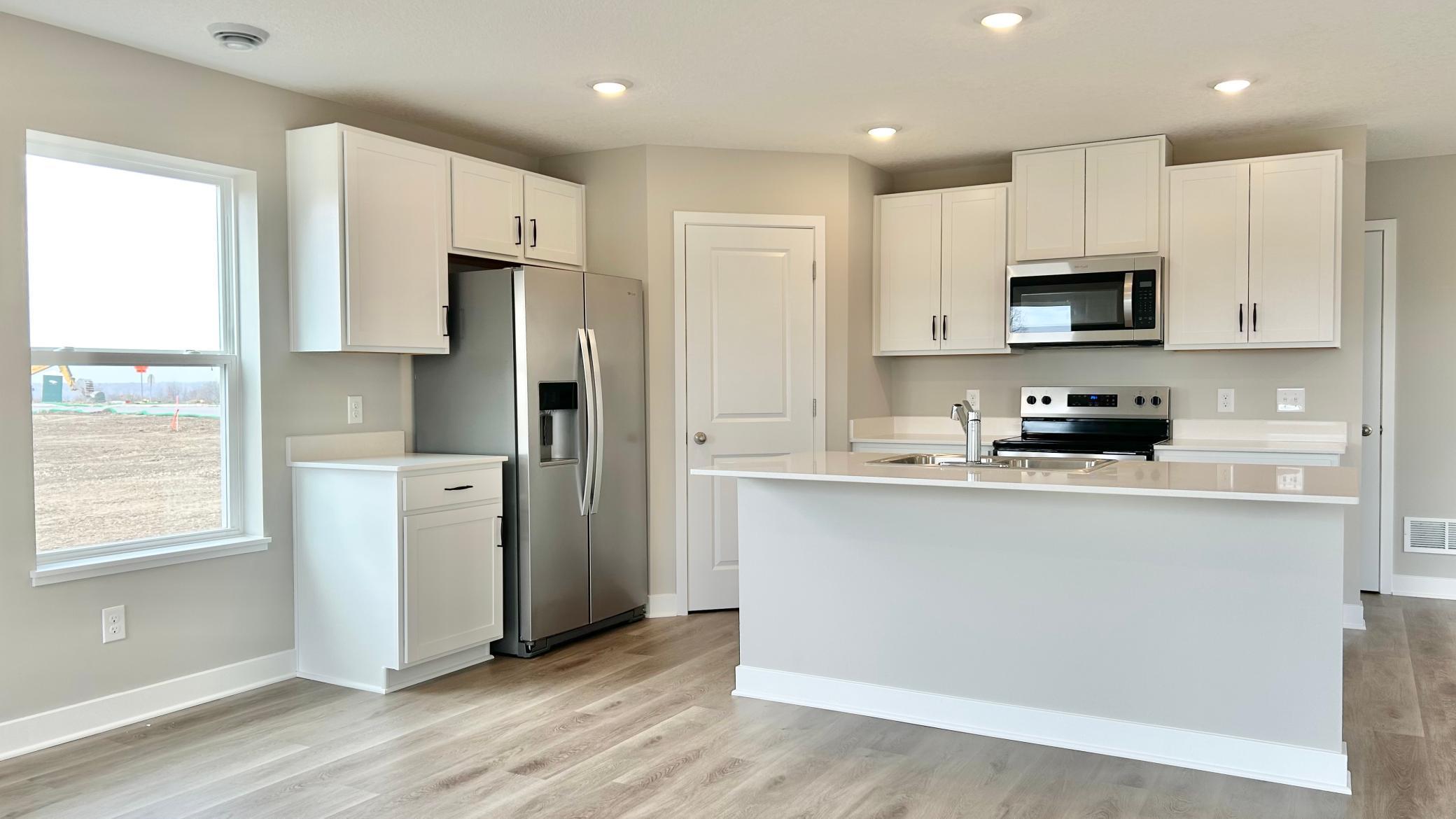 Spacious kitchen with white cabinetry and quartz countertops. Large island, providing ample seating!