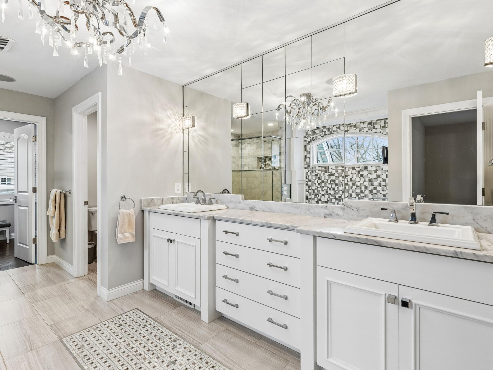 Double sinks with wall to wall mirrors. Door leads to water closet