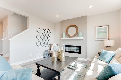 Living room with cozy electric fireplace and plenty of room for relaxing and entertaining. Model photo. Options and colors will vary.