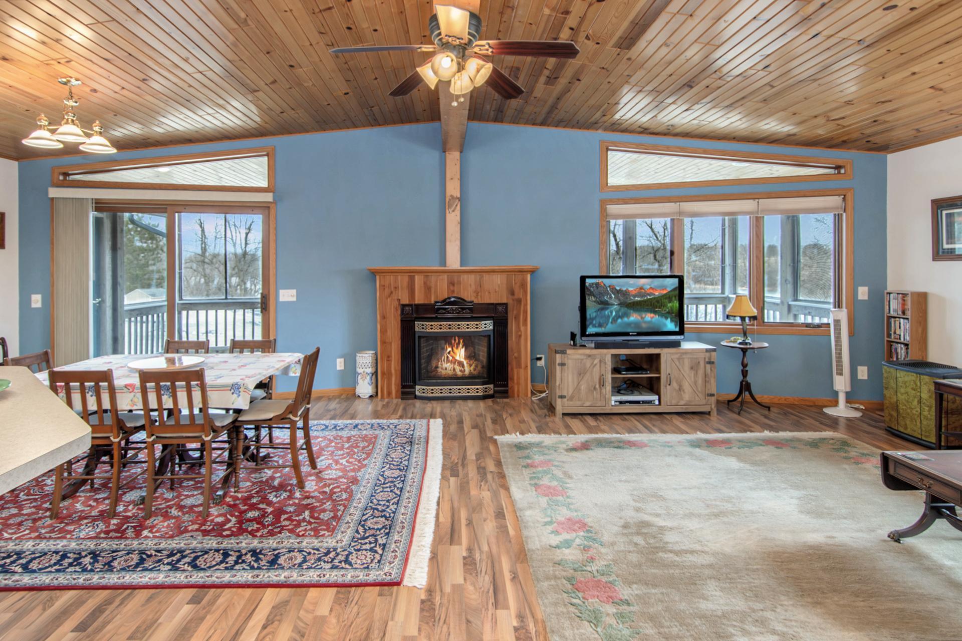 Open-concept living area with vaulted ceilings, fireplace, and panoramic lake views.