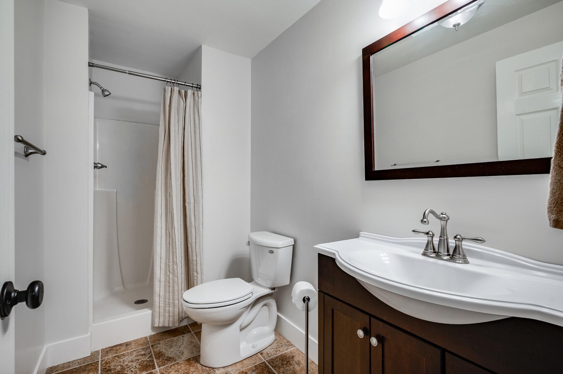 Lower level bath with tile floor and new vanity.