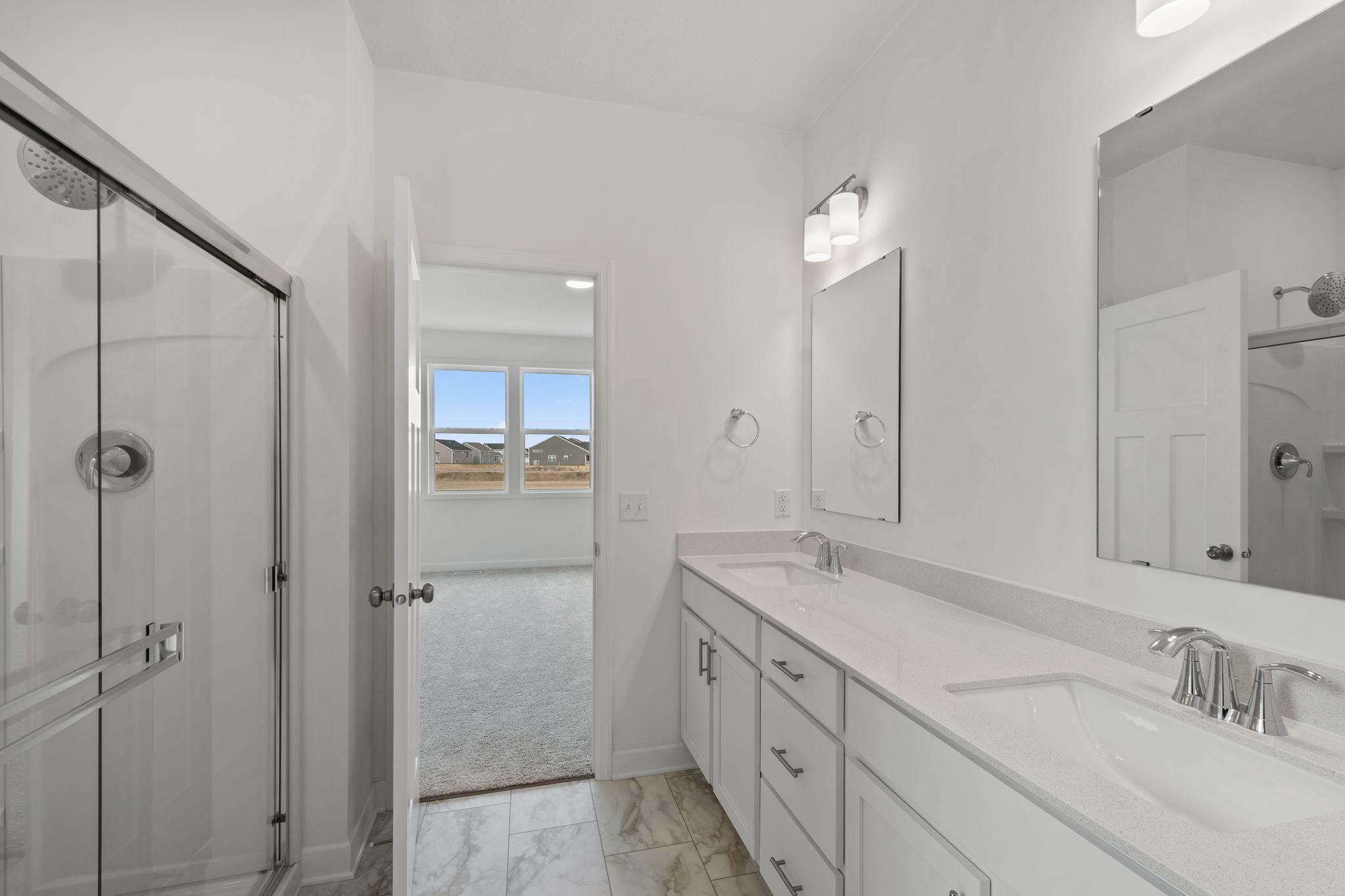 The glass-enclosed shower with full tile surround adds to a spa-like environment