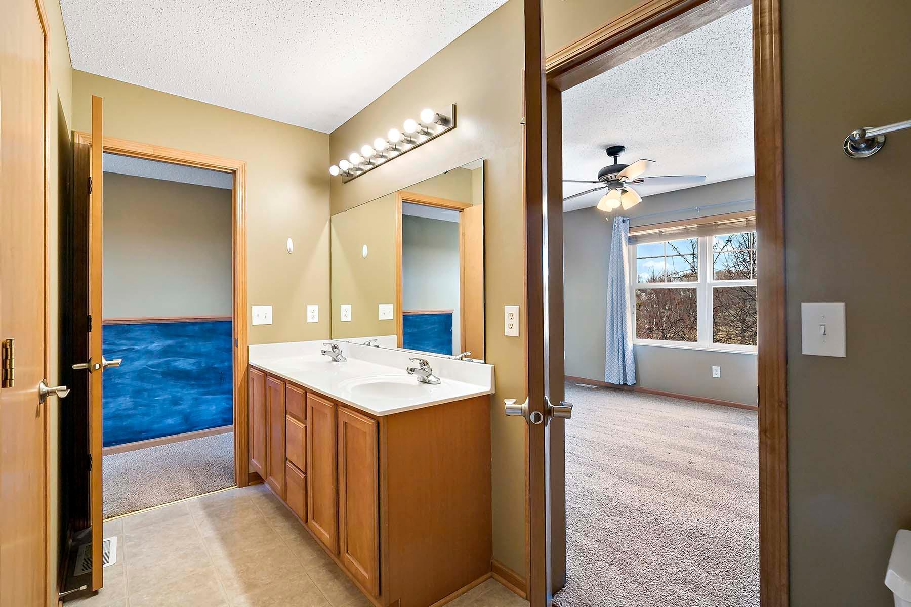 Bright ensuite bathroom attached to the primary bedroom with dual vanity and chalk board in the hallway for a do-to list or doodling.