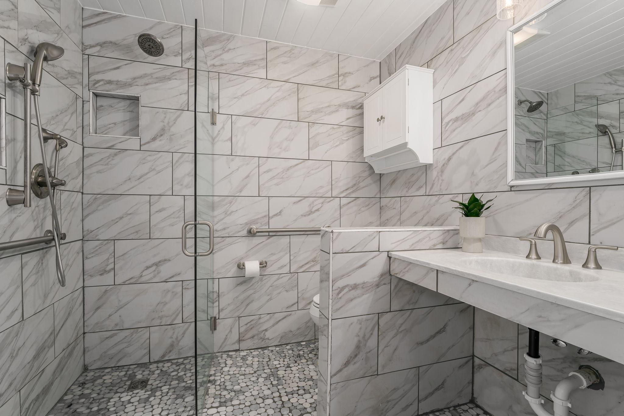 The recently updated main floor bath features a modern roll-in shower, offering both style and enhanced accessibility.