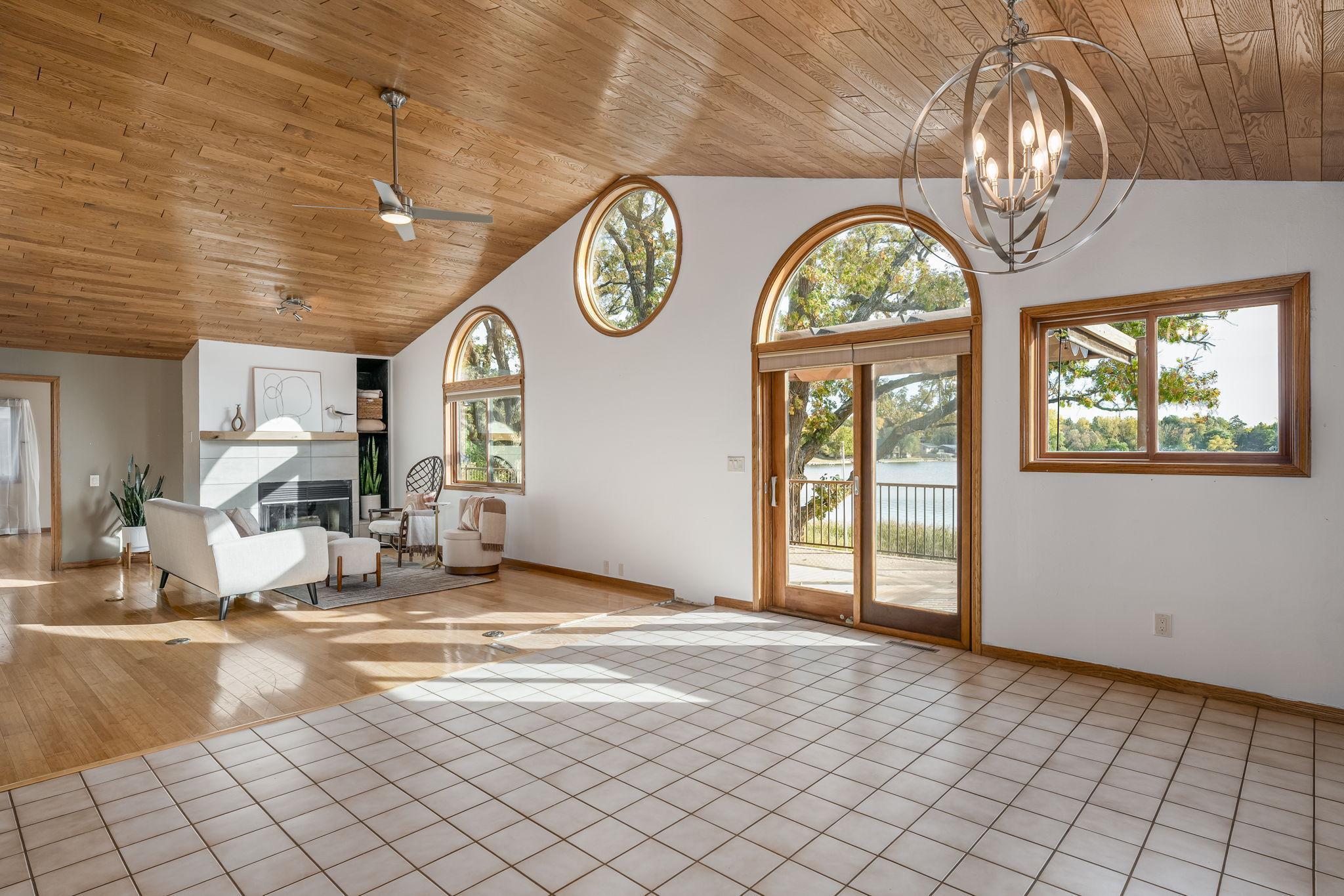 The vaulted living room, featuring beautiful wood floors, offers stunning views overlooking the lake, creating a serene and airy atmosphere.