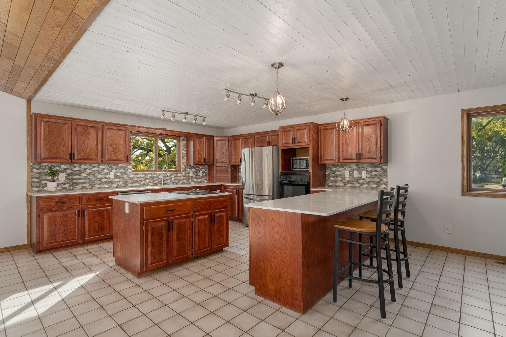 The kitchen boasts a center island with a cooktop, complemented by sleek stainless steel appliances and luxurious quartz countertops, offering both style and functionality.
