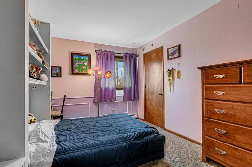 Upper level bedroom with wainscoting and a shelving unit with space beside it for a desk.