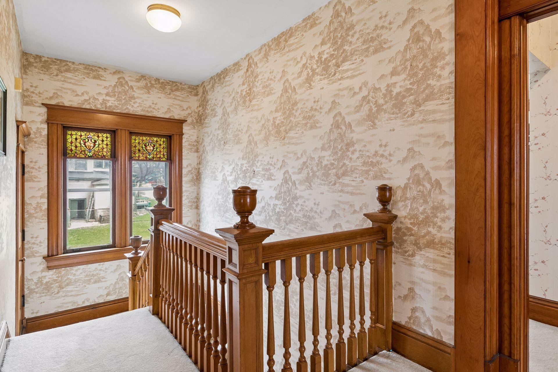 The landing with stunning banister, stain-glass windows and wide hallway