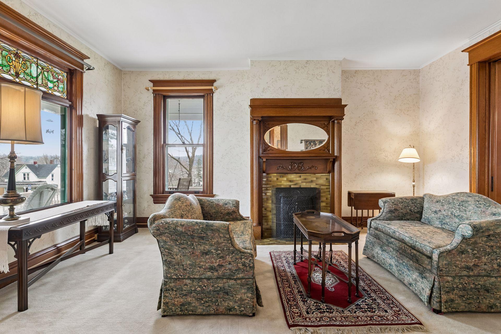 To the left of the entry is the formal living room with the wood burning fireplace, and stained-glass window