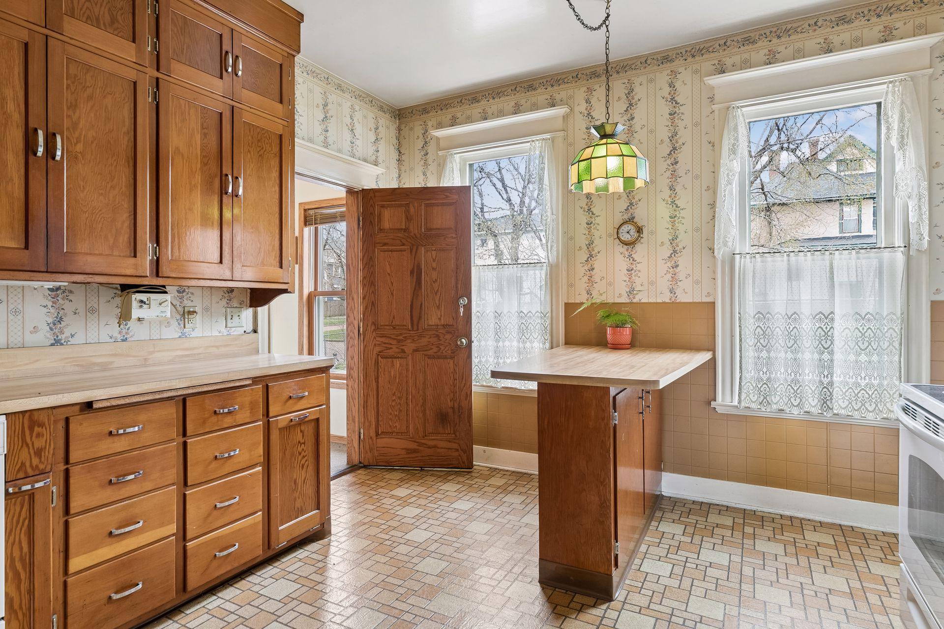 Kitchen with its original cabinets and door leading to the mudroom and garage access (attached). Additional side door to the yard
