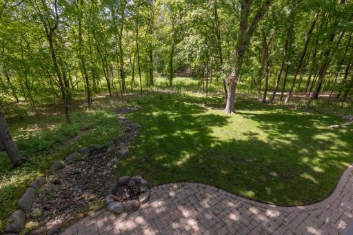 Outdoor patio and fire pit look out to wooded lot