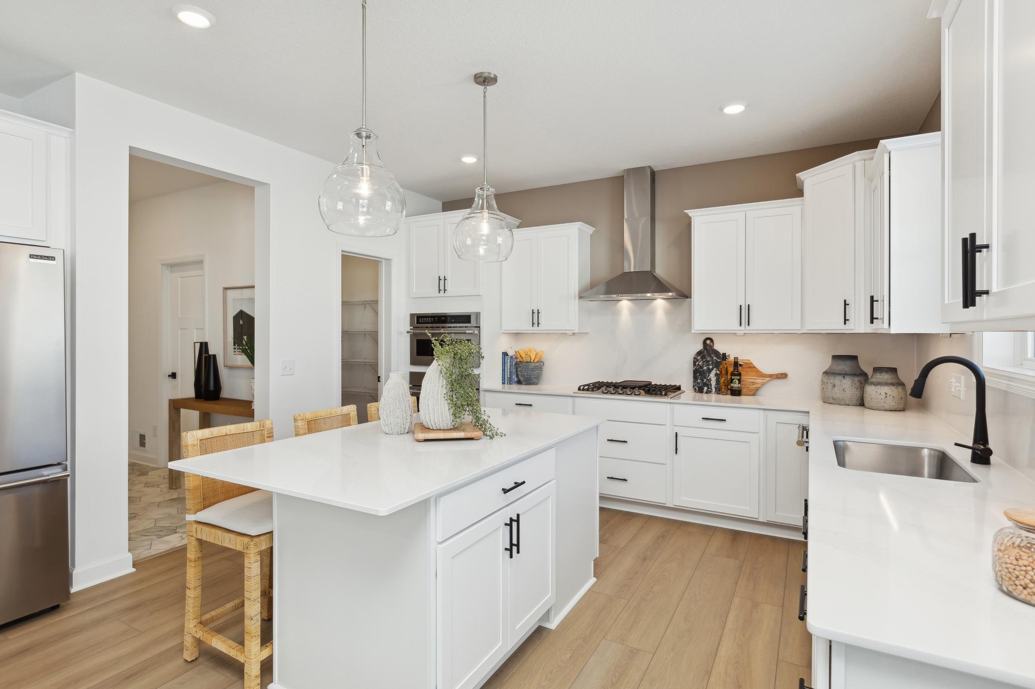 (Photo of decorated model, actual home's finishes will vary) This spacious gourmet kitchen features a large center island, quartz countertops, recessed lighting, LVP floors, stainless appliances and more!