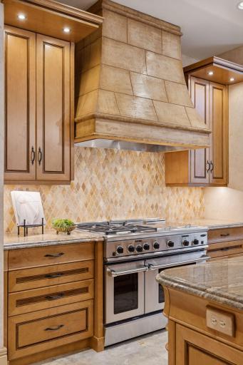 Stylish hood vent enhances the beautiful contrast between the tile and cabinetry.