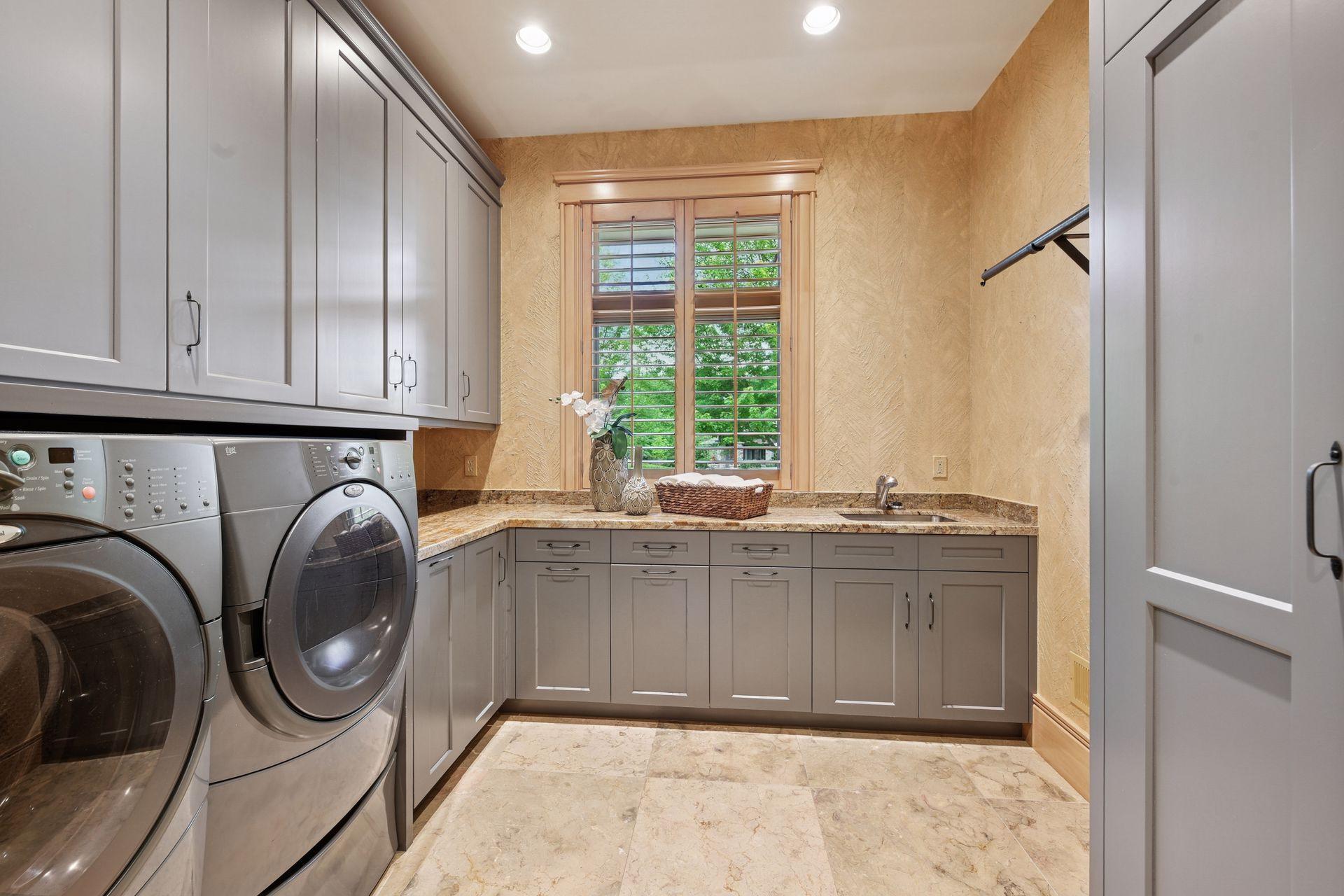 Spacious laundry room featuring a sink, hanging space, broom closet, and a dedicated gift-wrapping area.