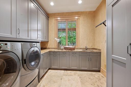 Spacious laundry room featuring a sink, hanging space, broom closet, and a dedicated gift-wrapping area.