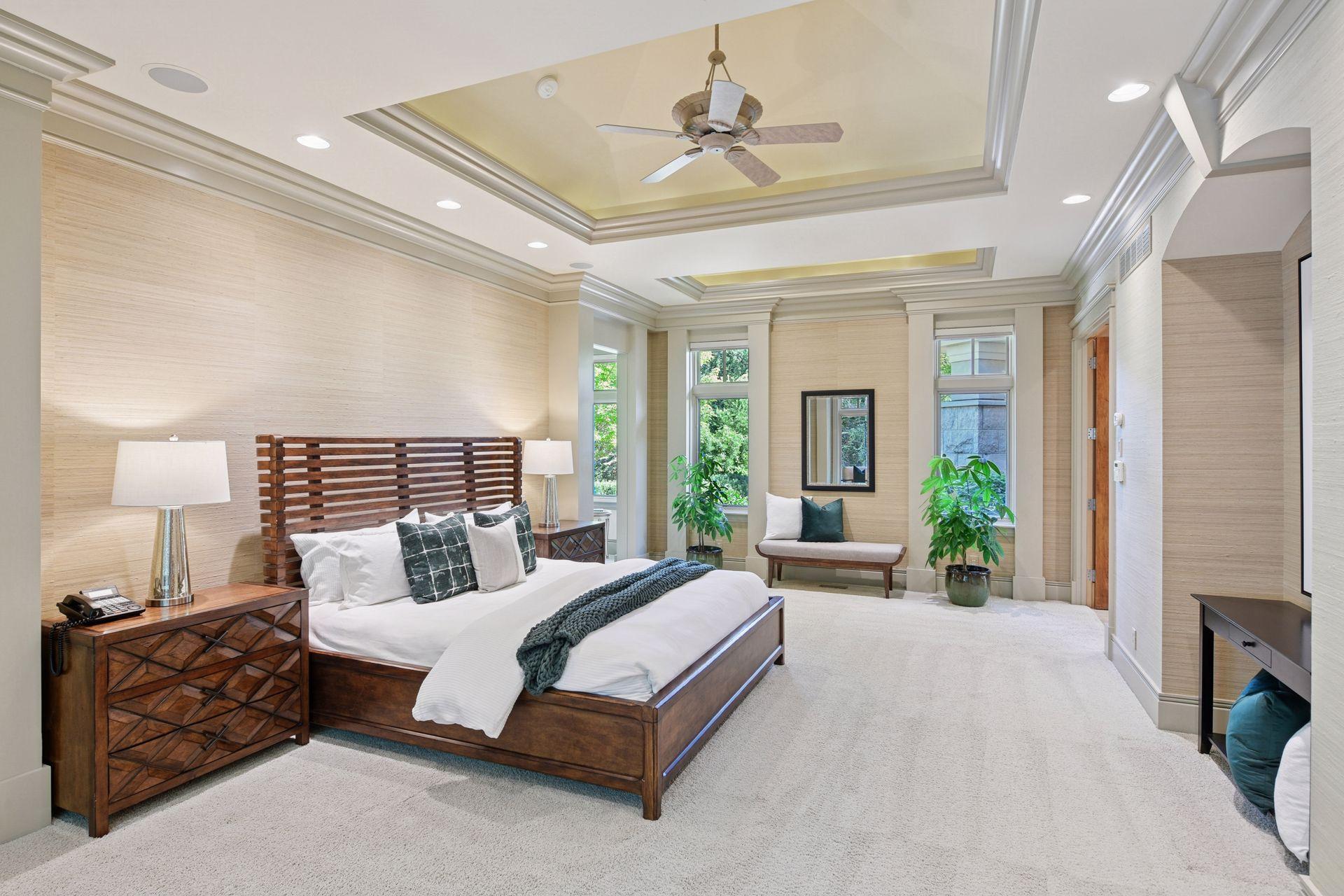 Generous primary suite privately positioned in its own wing, offering refined ceiling treatments and entry to a dressing area with two oversized walk-in closets.