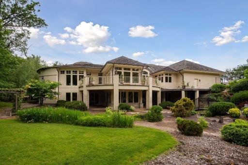 Lawn and gardens with path to bench on far side of pond.