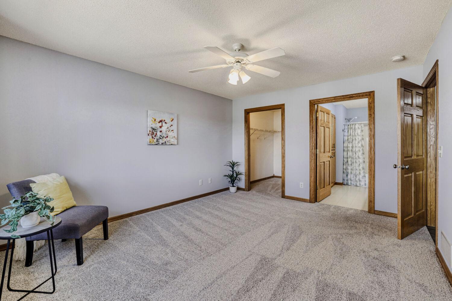 Another view of the main floor primary suite with a walk in closet and full bath.