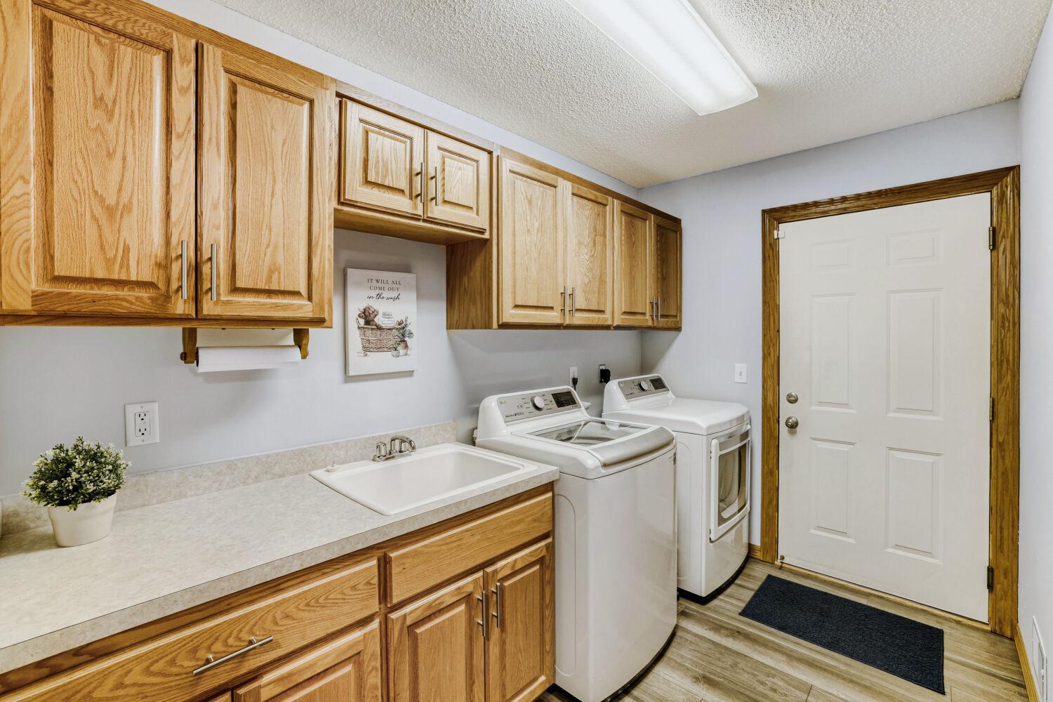 Laundry room with a sink and large closet that's located right off the garage entrance and down the hallway from the foyer and kitchen area.